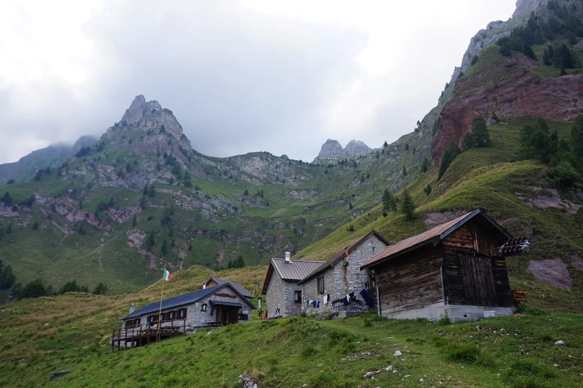 Rifugio Pian de Fontana mountain huts nestled on a grassy slope below rocky peaks.