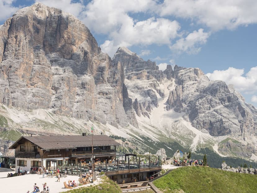 Rifugio Scoiattoli mountain hut with hikers below massive Dolomite peaks in summer.