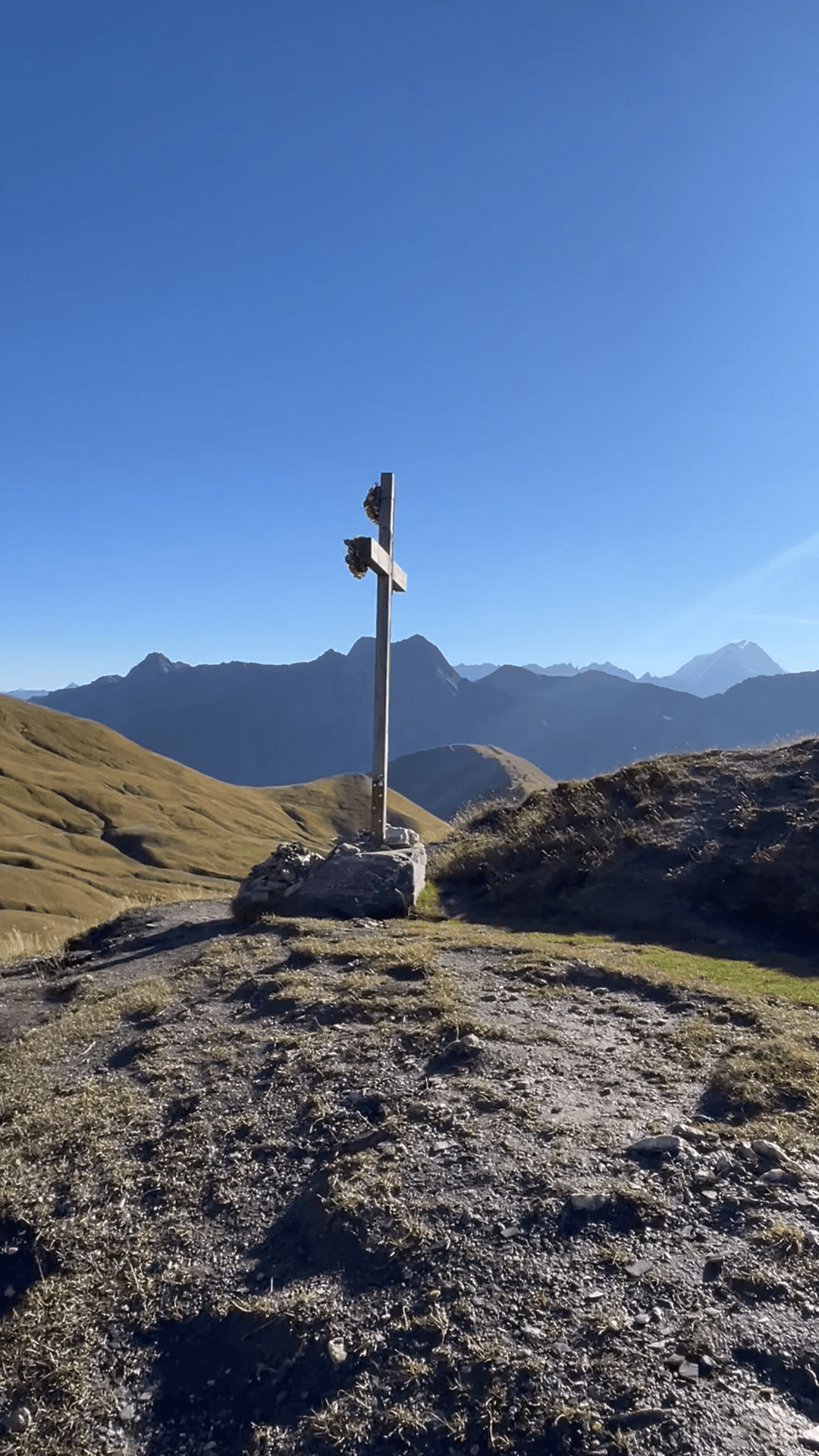 Wooden summit cross on alpine mountain ridge with clear blue sky