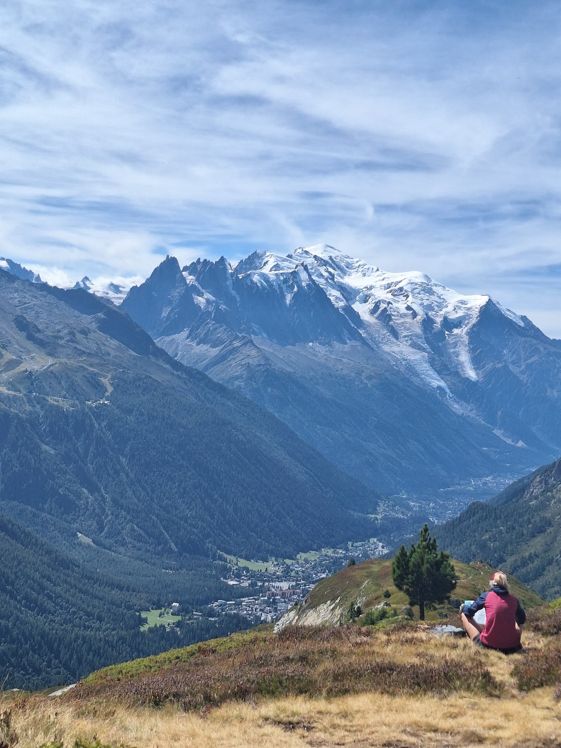 Hiker resting above Chamonix Valley with snow-capped mountain peaks
