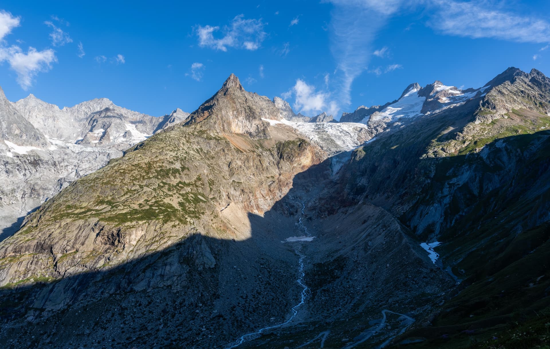 Glacier valley with rugged mountain peaks and morning light under a blue sky