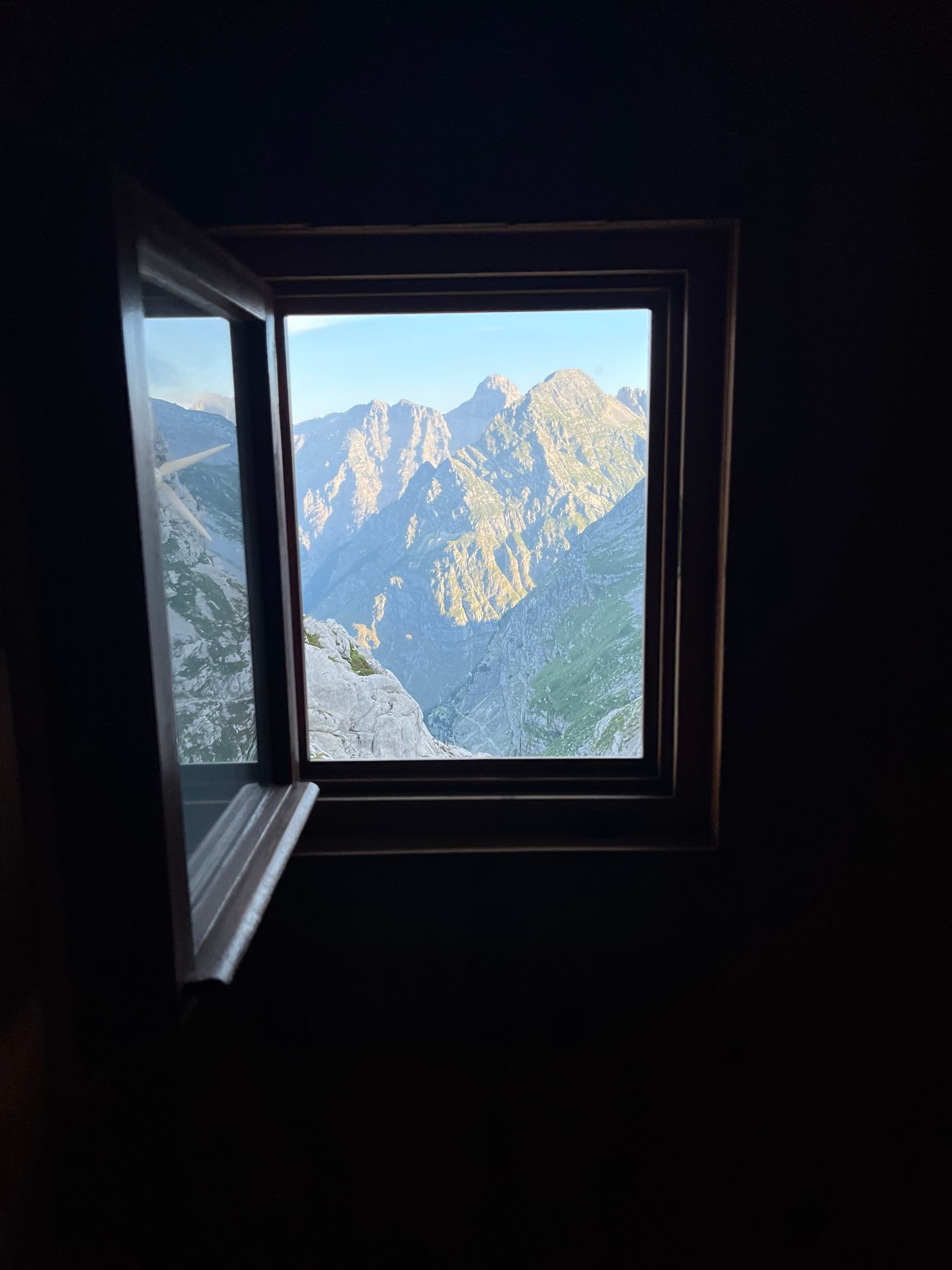 Mountain peaks viewed through an open wooden hut window