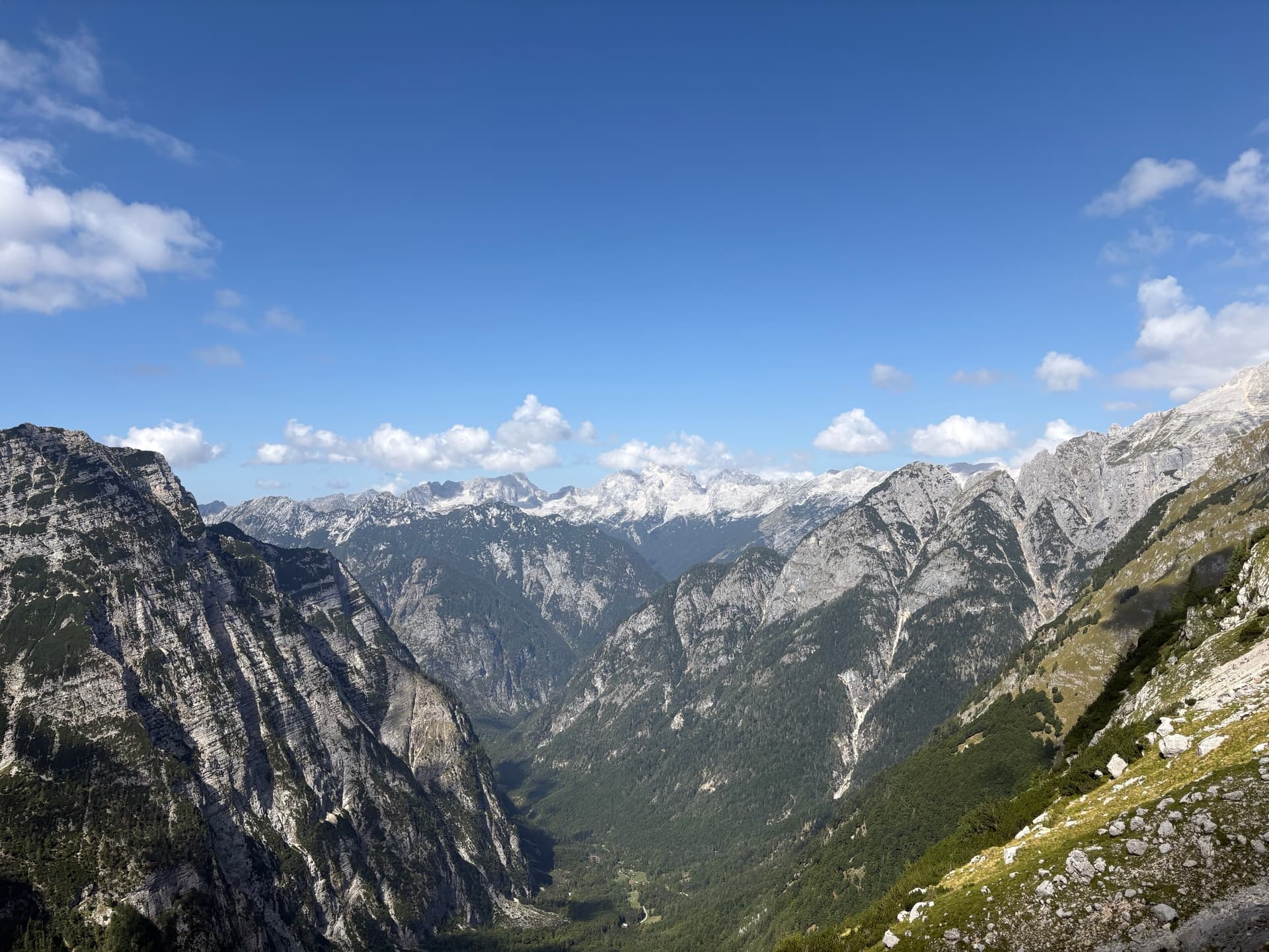 High valley between rugged limestone peaks with green slopes and blue sky