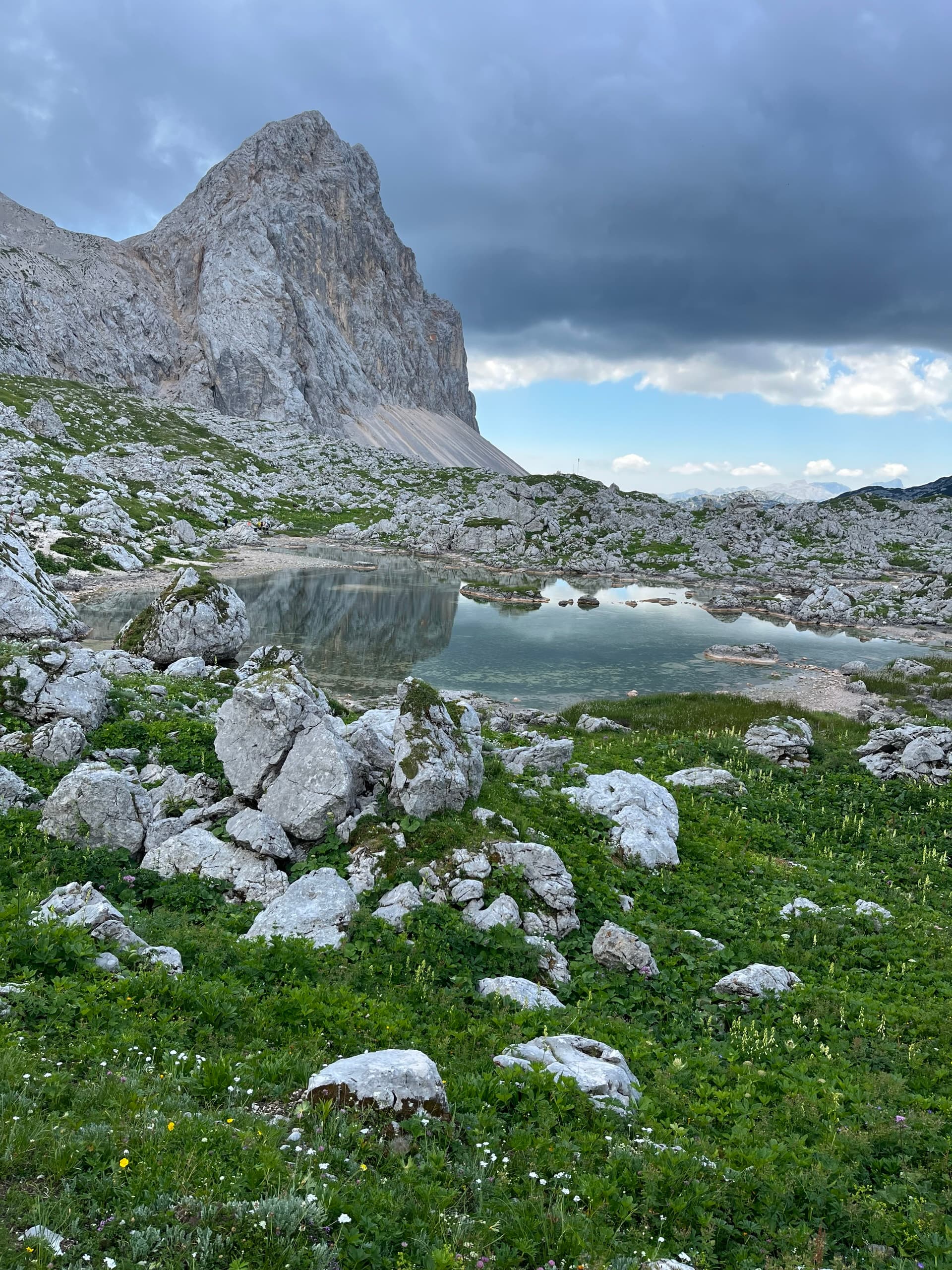 Alpine tarn reflecting a rocky mountain peak under a cloudy sky