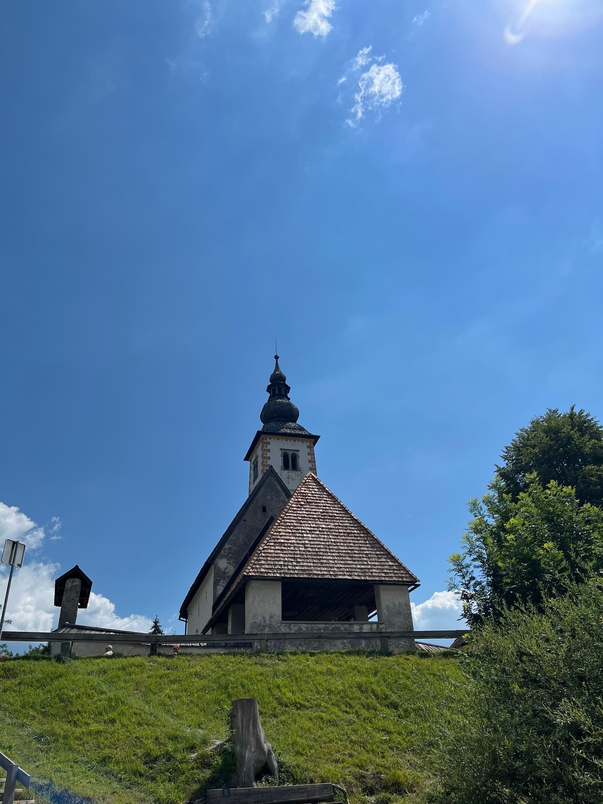 Small historic church on a green grassy hill under a blue sky