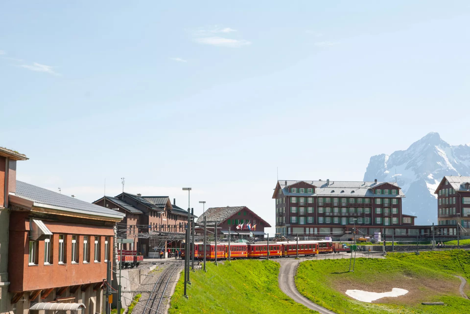 Kleine Scheidegg train station with red mountain railway and snow-capped peaks in background.