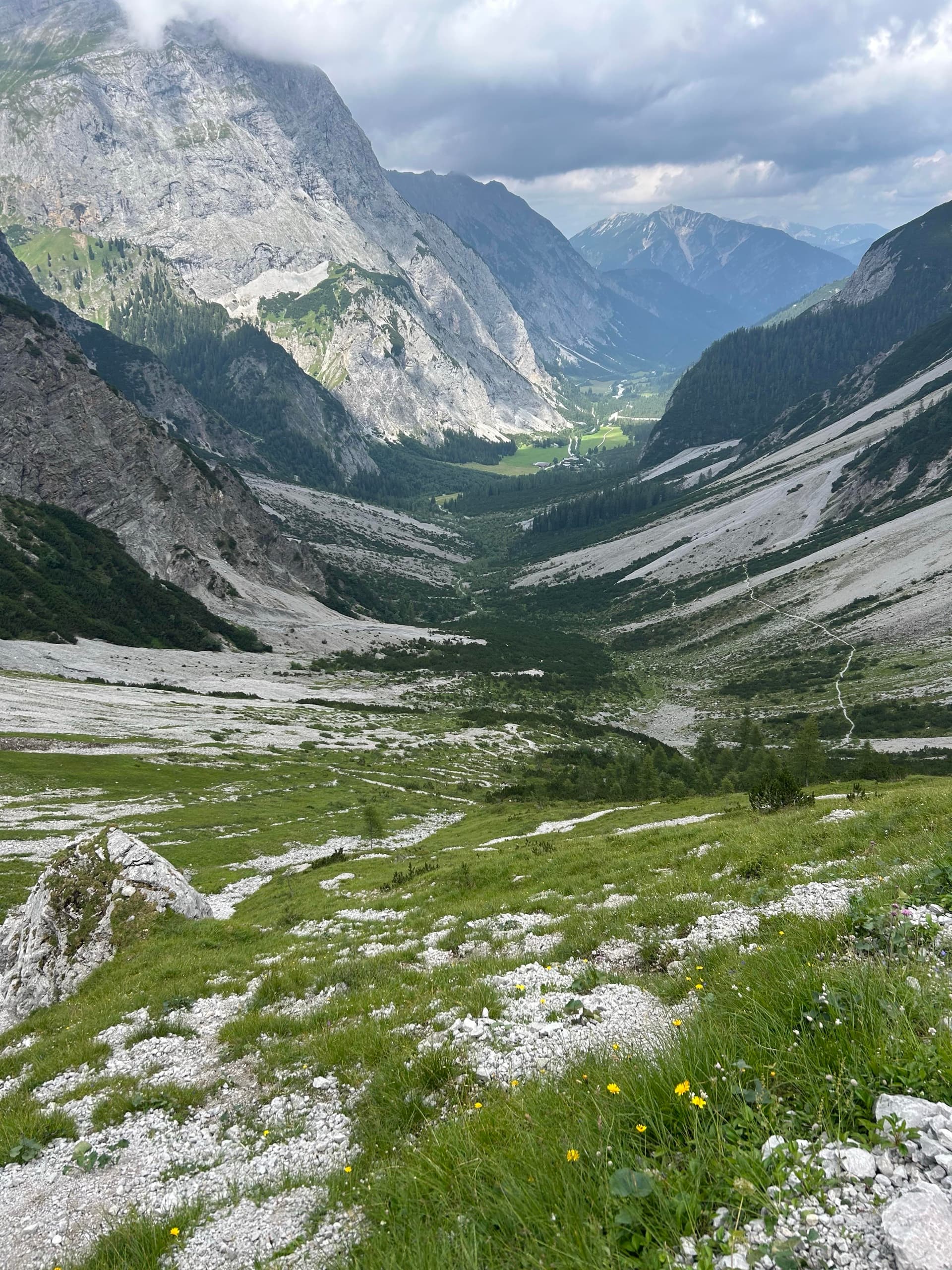 Green valley below sheer mountain peaks and rocky slopes