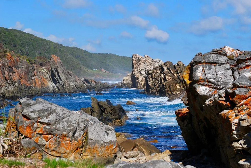 View back at the start point of the Otter Trail at Tsitsikamma National Park in South Africa, with big rock formations, blue sky with some clouds